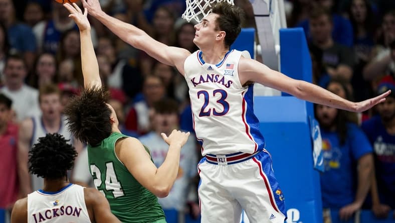 Nov 10, 2023; Lawrence, Kansas, USA; Kansas Jayhawks forward Parker Braun (23) blocks the shot of Manhattan Jaspers forward Xinyi Li (24) during the first half at Allen Fieldhouse. Mandatory Credit: Jay Biggerstaff-USA TODAY Sports