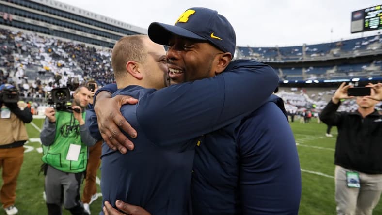 Nov 11, 2023; University Park, Pennsylvania, USA; Michigan Wolverines offensive line coach Sherrone Moore hugs an assistant coach following a game against the Penn State Nittany Lions at Beaver Stadium. Michigan won 24-15. Mandatory Credit: Matthew O'Haren-USA TODAY Sports
