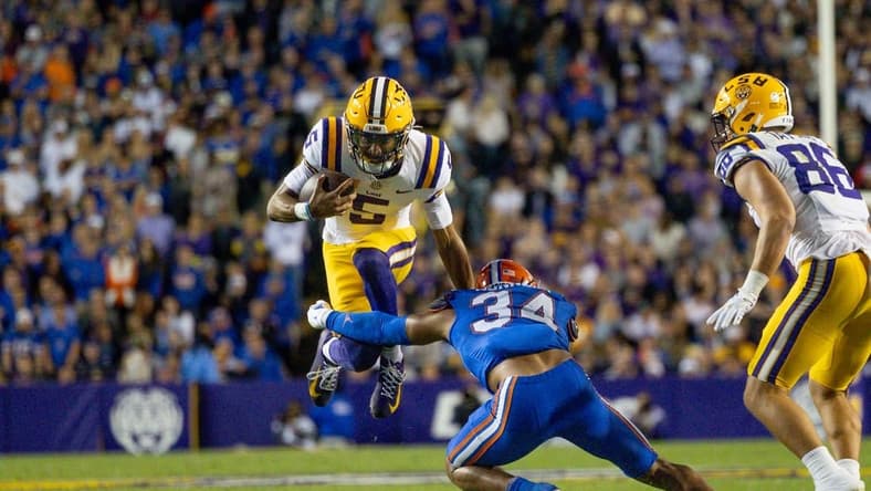 Nov 11, 2023; Baton Rouge, Louisiana, USA;  LSU Tigers quarterback Jayden Daniels (5) attempts to leap over the arms of Florida Gators linebacker Mannie Nunnery (34) during the first half at Tiger Stadium. Mandatory Credit: Stephen Lew-USA TODAY Sports
