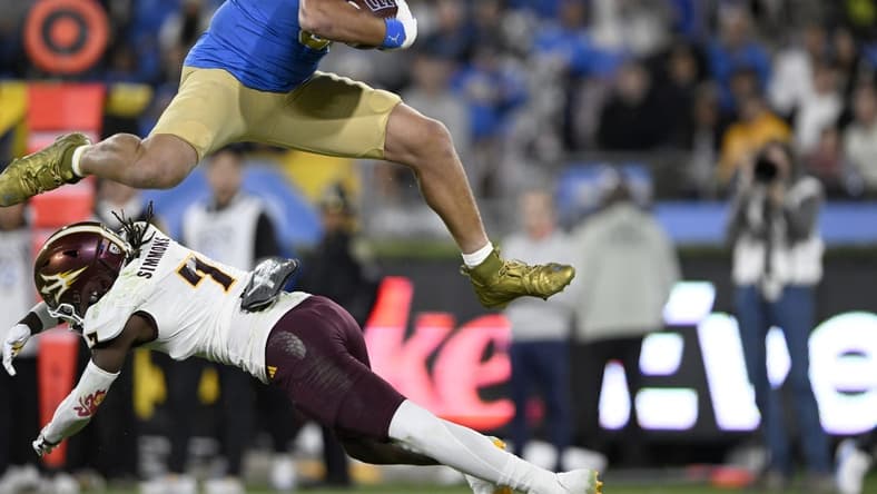 Nov 11, 2023; Pasadena, California, USA;  UCLA Bruins tight end Moliki Matavao (88) leaps over Arizona State Sun Devils defensive back Shamari Simmons (7) after making a catch during the first half at the Rose Bowl. Mandatory Credit: Alex Gallardo-USA TODAY Sports