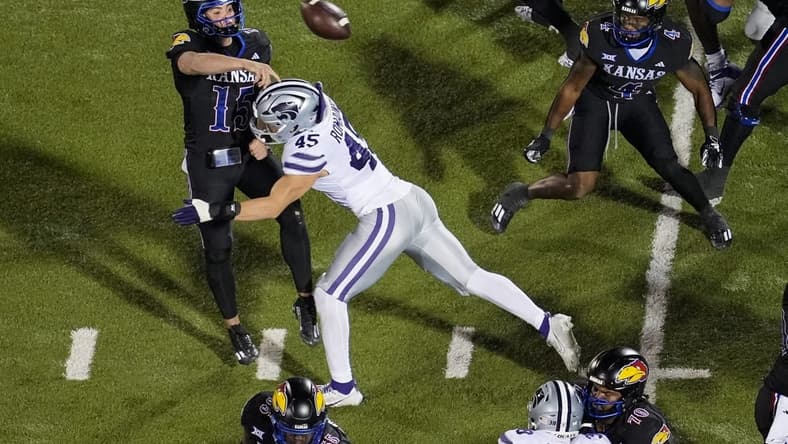Nov 18, 2023; Lawrence, Kansas, USA; Kansas Jayhawks quarterback Cole Ballard (15) throws a touchdown pass as he is hit by Kansas State Wildcats linebacker Austin Romaine (45) during the first half at David Booth Kansas Memorial Stadium. Mandatory Credit: Jay Biggerstaff-USA TODAY Sports