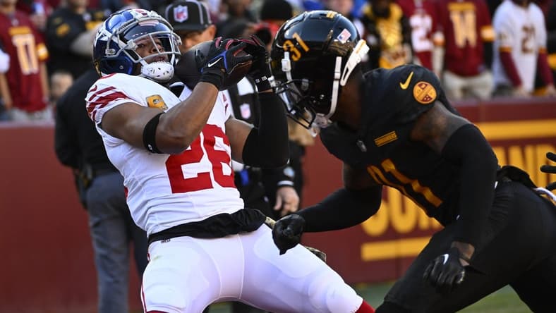 Nov 19, 2023; Landover, Maryland, USA; New York Giants running back Saquon Barkley (26) catches a touchdown  past Washington Commanders safety Kamren Curl (31) during the first half at FedExField. Mandatory Credit: Brad Mills-USA TODAY Sports