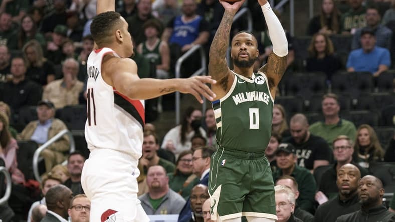 Nov 26, 2023; Milwaukee, Wisconsin, USA;  Milwaukee Bucks guard Damian Lillard (0) shoots against Portland Trail Blazers guard Malcolm Brogdon (11) during the first quarter at Fiserv Forum. Mandatory Credit: Jeff Hanisch-USA TODAY Sports