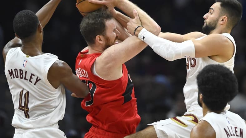 Nov 26, 2023; Cleveland, Ohio, USA; Cleveland Cavaliers forward Evan Mobley (4) and guard Max Strus (1) defend Toronto Raptors center Jakob Poeltl (19) in the second quarter at Rocket Mortgage FieldHouse. Mandatory Credit: David Richard-USA TODAY Sports