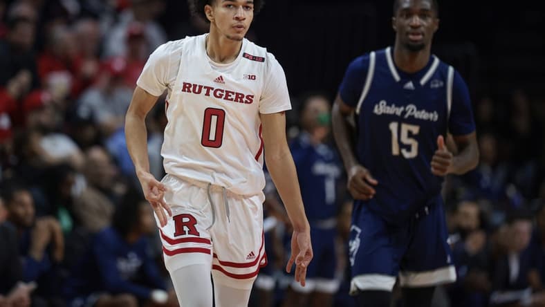 Nov 27, 2023; Piscataway, New Jersey, USA;  Rutgers Scarlet Knights guard Derek Simpson (0) reacts after making a three point basket in front of St. Peter's Peacocks forward Stephon Roberts (15) during the first half at Jersey Mike's Arena. Mandatory Credit: Vincent Carchietta-USA TODAY Sports