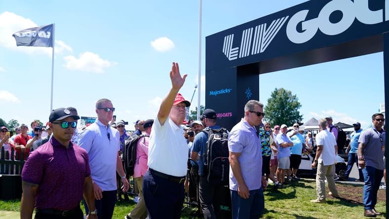 Former President Donald Trump waves to the crowd as he exits the putting green with his aide Walt Nauta, left, during the final round of the LIV Golf Bedminster golf tournament at Trump National Bedminster on Sunday, Aug. 13, 2023.