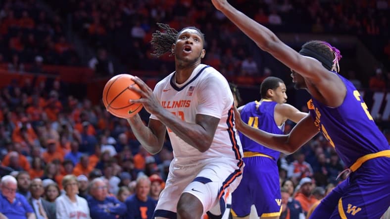Nov 24, 2023; Champaign, Illinois, USA; Illinois Fighting Illini forward Dain Dainja (42) drives to the basket as Western Illinois Leathernecks center Drew Cisse (23) defends during the first half at State Farm Center. Mandatory Credit: Ron Johnson-USA TODAY Sports