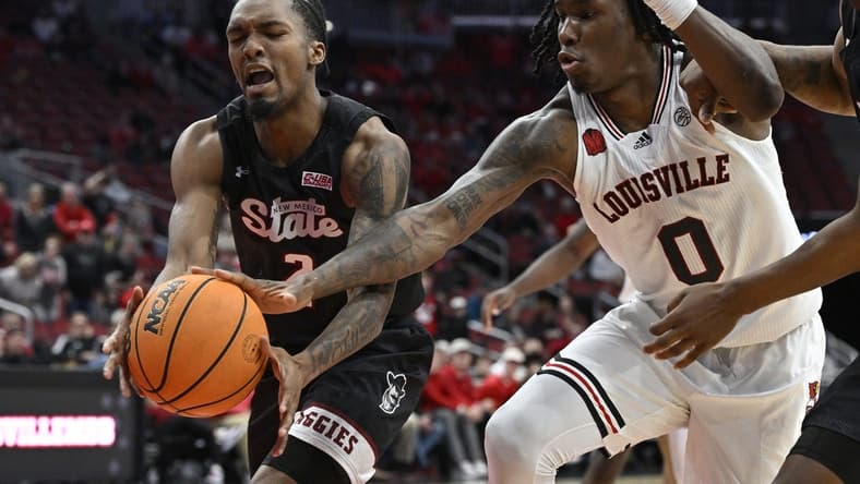 Nov 26, 2023; Louisville, Kentucky, USA; Louisville Cardinals guard Mike James (0) scrambles for the ball against New Mexico State Aggies guard Jordan Rawls (2) during overtime at KFC Yum! Center. Louisville defeated New Mexico State 90-84. Mandatory Credit: Jamie Rhodes-USA TODAY Sports