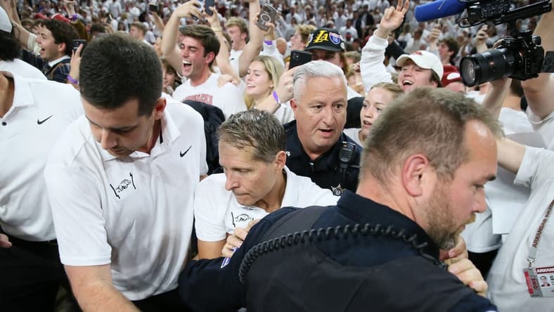Nov 29, 2023; Fayetteville, Arkansas, USA; Arkansas Razorbacks head coach Eric Musselman is ushered off of the court by police after the game against the Duke Blue Devils at Bud Walton Arena. Arkansas won 80-75. Mandatory Credit: Nelson Chenault-USA TODAY Sports.