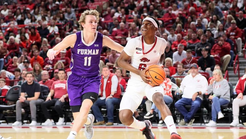 Dec 4, 2023; Fayetteville, Arkansas, USA; Arkansas Razorbacks guard Layden Blocker (6) drives against Furman Paladins guard Carter Whitt (11) during the first half at Bud Walton Arena. Mandatory Credit: Nelson Chenault-USA TODAY Sports