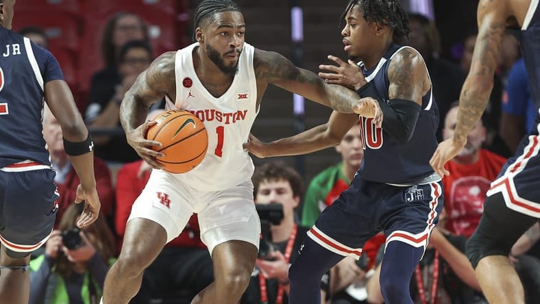 Dec 9, 2023; Houston, Texas, USA; Houston Cougars guard Jamal Shead (1) controls the ball as Jackson State Tigers guard Chase Adams (10) defends during the first half at Fertitta Center. Mandatory Credit: Troy Taormina-USA TODAY Sports