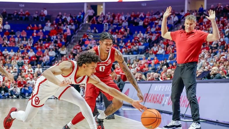 Oklahoma guard Milos Uzan (12) and Arkansas guard Khalif Battle (0) fight for a ball going out-of-bounds during an NCAA basketball game between the Oklahoma Sooners and the Arkansas Razorbacks at the BOK Center in Tulsa, Okla., on Saturday, Dec. 9, 2023.