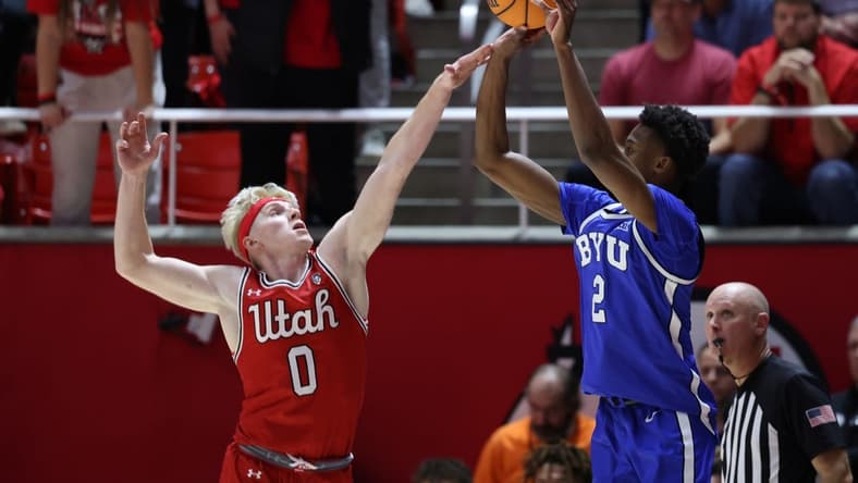 Dec 9, 2023; Salt Lake City, Utah, USA; Brigham Young Cougars guard Jaxson Robinson (2) is fouled by Utah Utes guard Hunter Erickson (0) shooting a three point shot during the second half at Jon M. Huntsman Center. Mandatory Credit: Rob Gray-USA TODAY Sports