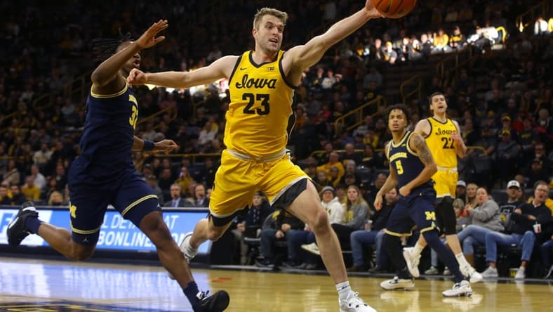 Iowa s Ben Krikke (23) reaches for a ball, attempting to keep it inbounds Sunday, Dec. 10, 2023 at Carver-Hawkeye Arena in Iowa City, Iowa.