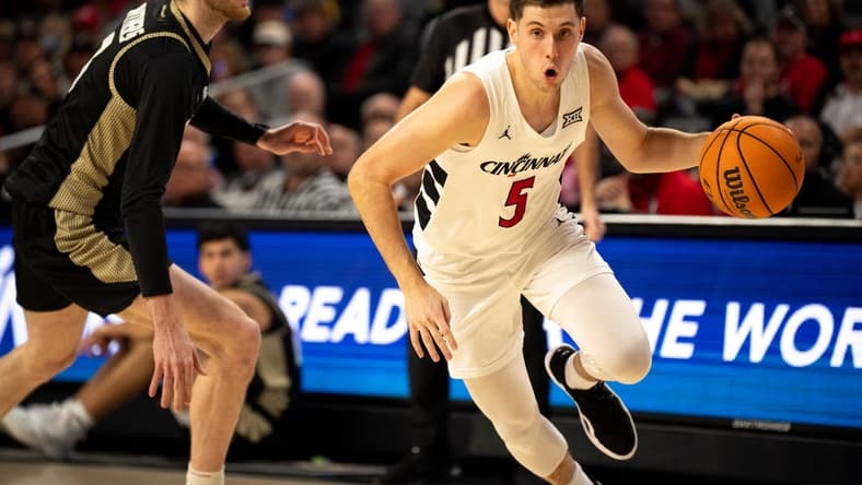 Cincinnati Bearcats guard CJ Fredrick (5) drives passed Bryant Bulldogs forward Connor Withers (7) in the first half of the NCAA Basketball game between the Bryant Bulldogs and Cincinnati Bearcats at Fifth Third Arena in Cincinnati on Tuesday, Dec. 12, 2023.