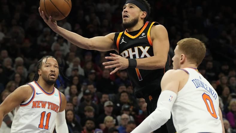 Dec 15, 2023; Phoenix, Arizona, USA; Phoenix Suns guard Devin Booker (1) drives between New York Knicks guard Jalen Brunson (11) and  guard Donte DiVincenzo (0) in the first half at Footprint Center. Mandatory Credit: Rick Scuteri-USA TODAY Sports