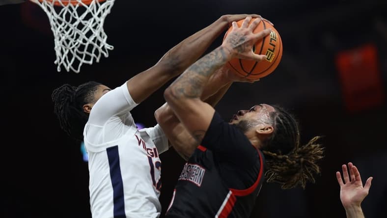 Dec 16, 2023; Charlottesville, Virginia, USA; Virginia Cavaliers guard Elijah Gertrude (12) blocks the shot of Northeastern Huskies guard Joe Pridgen (0) in the first half at John Paul Jones Arena. Mandatory Credit: Geoff Burke-USA TODAY Sports