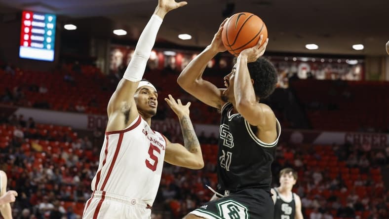 Dec 16, 2023; Norman, Oklahoma, USA; Green Bay Phoenix guard Noah Reynolds (21) shoots against Oklahoma Sooners guard Rivaldo Soares (5) during the first half at Lloyd Noble Center. Mandatory Credit: Alonzo Adams-USA TODAY Sports