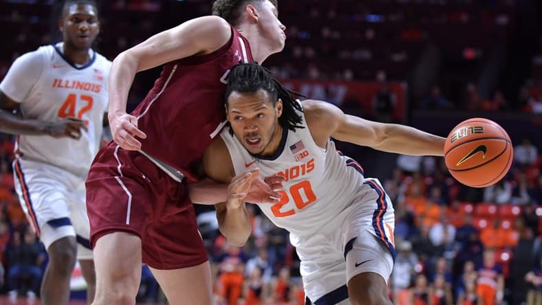 Dec 17, 2023; Champaign, Illinois, USA; Illinois Fighting Illini forward Ty Rodgers (20) drives the ball against Colgate Raiders guard Brady Cummins (1) during the first half at State Farm Center. Mandatory Credit: Ron Johnson-USA TODAY Sports