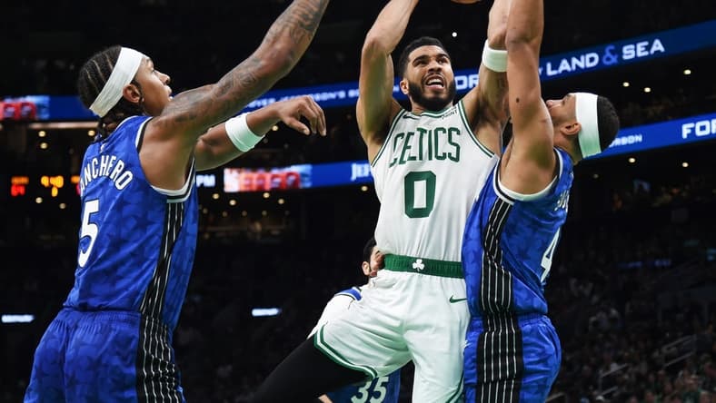 Dec 17, 2023; Boston, Massachusetts, USA;  Boston Celtics forward Jayson Tatum (0) drives to the basket between Orlando Magic forward Paolo Banchero (5) and guard Jalen Suggs (4) during the second half at TD Garden. Mandatory Credit: Bob DeChiara-USA TODAY Sports