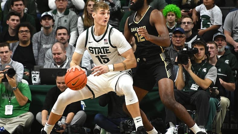 Dec 18, 2023; East Lansing, Michigan, USA; Michigan State Spartans center Carson Cooper (15) dribbles the ball against Oakland Golden Grizzlies forward Tuburu Naivalurua (12) during the first half at Jack Breslin Student Events Center. Mandatory Credit: Dale Young-USA TODAY Sports