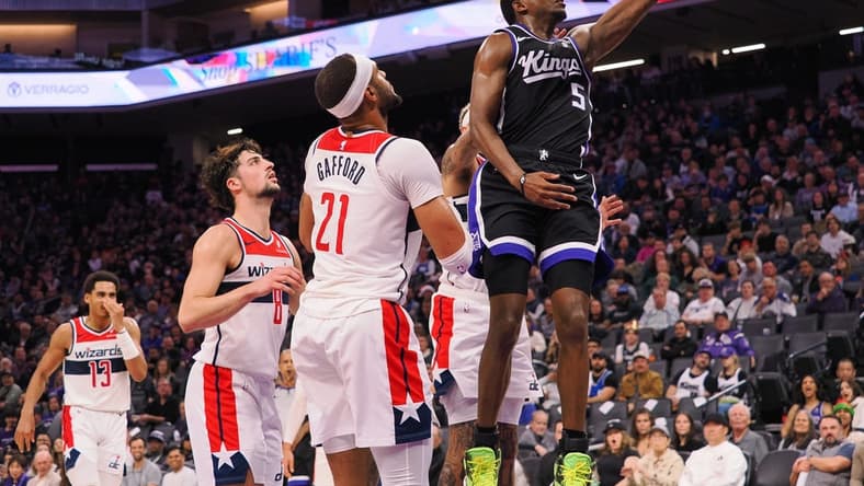 Dec 18, 2023; Sacramento, California, USA; Sacramento Kings guard De'Aaron Fox (5) scores a layup against Washington Wizards center Daniel Gafford (21) during the second quarter at Golden 1 Center. Mandatory Credit: Kelley L Cox-USA TODAY Sports