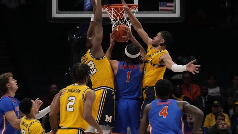 Dec 19, 2023; Charlotte, North Carolina, USA; Florida Gators guard Walter Clayton Jr. (1) is sandwiched at the basket by Michigan Wolverines forward Tarris Reed Jr. (32) and forward Olivier Nkamhoua (13) during the first half at Spectrum Center. Mandatory Credit: Jim Dedmon-USA TODAY Sports