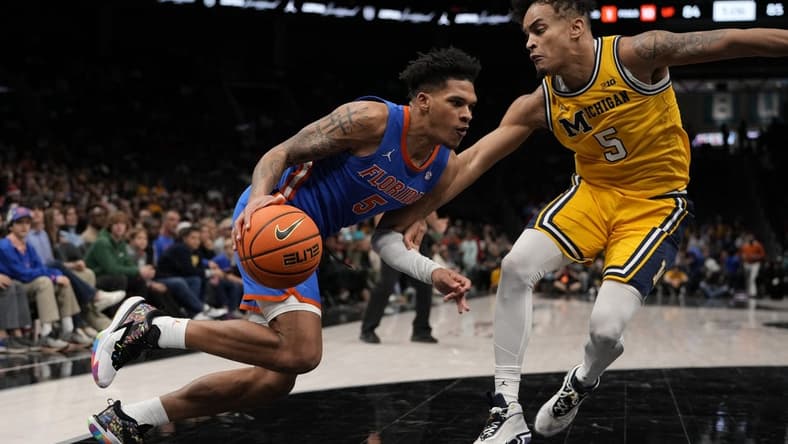 Dec 19, 2023; Charlotte, North Carolina, USA; Florida Gators guard Will Richard (5) drives to the basket against Michigan Wolverines forward Terrance Williams II (5) during the first overtime period at Spectrum Center. Mandatory Credit: Jim Dedmon-USA TODAY Sports