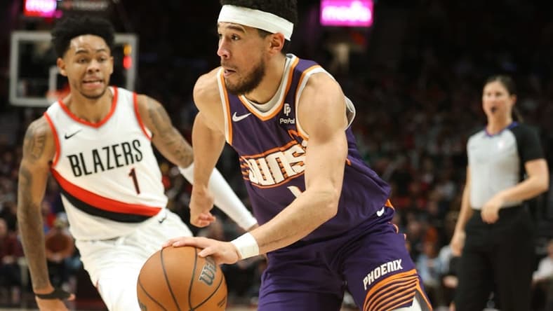 Dec 19, 2023; Portland, Oregon, USA; Phoenix Suns guard Devin Booker (1) drives the ball past Portland Trail Blazers guard Anfernee Simons (1) in the third quarter at Moda Center. Mandatory Credit: Jaime Valdez-USA TODAY Sports