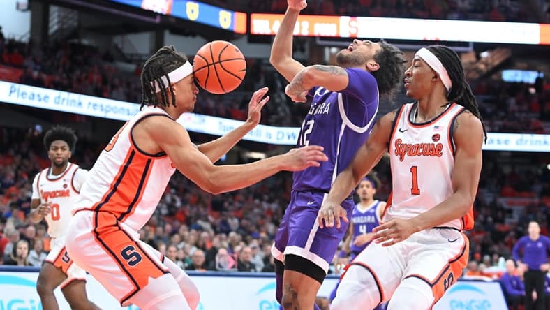Dec 21, 2023; Syracuse, New York, USA; Syracuse Orange forward Benny Williams (13) has the ball hit his head on a drive by Niagara Purple Eagles guard Kwane Marble (12) with forward Maliq Brown (1) in the first half at the JMA Wireless Dome. Mandatory Credit: Mark Konezny-USA TODAY Sports
