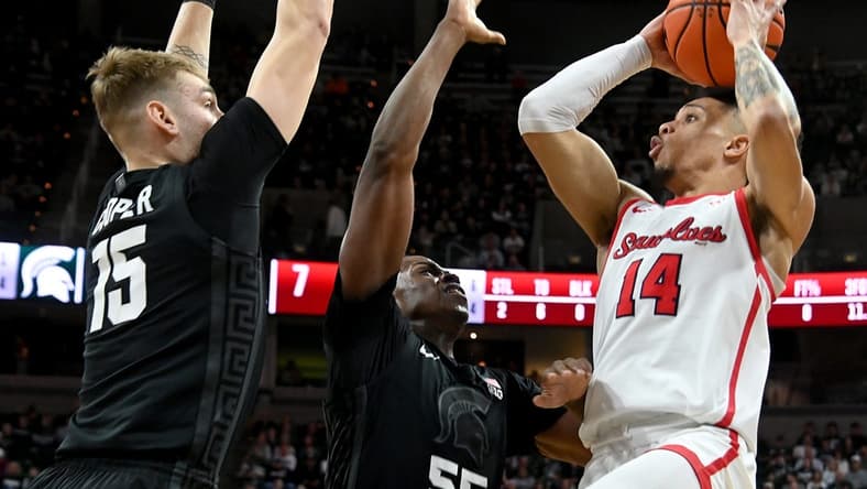Dec 21, 2023; East Lansing, Michigan, USA; Stony Brook Seawolves guard Tyler Stephenson-Moore (14)can t see an open shot past the defense of Michigan State Spartans forward Coen Carr (55) and Michigan State Spartans center Carson Cooper (15) at Jack Breslin Student Events Center. Mandatory Credit: Dale Young-USA TODAY Sports