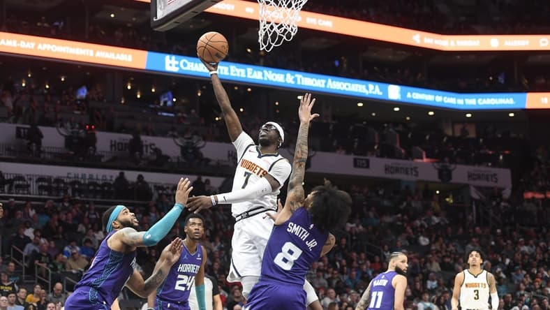 Dec 23, 2023; Charlotte, North Carolina, USA; Denver Nuggets guard Reggie Jackson (7) drives against Charlotte Hornets forward Miles Bridges (0) and guard Nick Smith Jr. (8) during the first half at the Spectrum Center. Mandatory Credit: Sam Sharpe-USA TODAY Sports