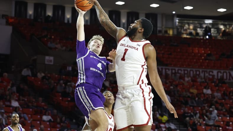 Dec 28, 2023; Norman, Oklahoma, USA; Central Arkansas Bears guard Johannes Kirsipuu (4) shoots as Oklahoma Sooners forward John Hugley IV (1) defends during the first half at Lloyd Noble Center. Mandatory Credit: Alonzo Adams-USA TODAY Sports