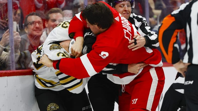 Dec 31, 2023; Detroit, Michigan, USA; Detroit Red Wings defenseman Ben Chiarot (8) scuffles with Boston Bruins center Morgan Geekie (39) while linesman Derek Amell (75) tries to separate them during the first period of the game between the Boston Bruins and the Detroit Red Wings at Little Caesars Arena. Mandatory Credit: Brian Bradshaw Sevald-USA TODAY Sports
