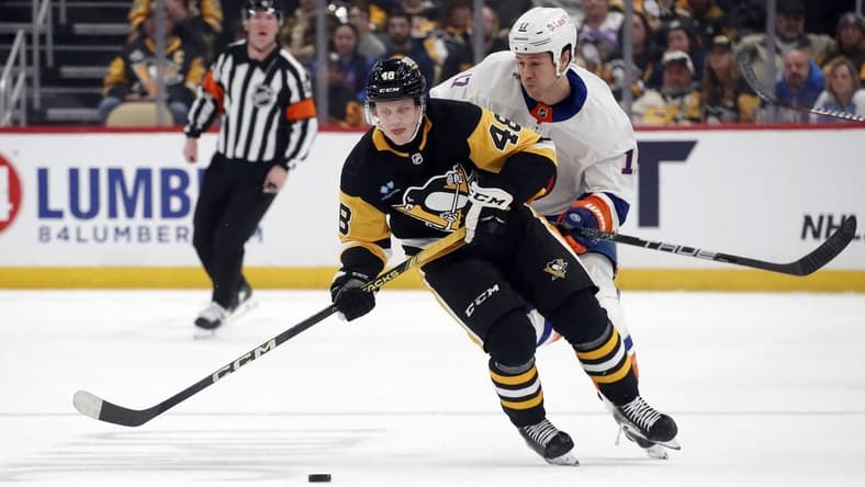 Dec 31, 2023; Pittsburgh, Pennsylvania, USA; Pittsburgh Penguins right wing Valtteri Puustinen (48) moves the puck ahead of New York Islanders left wing Matt Martin (17) during the first period at PPG Paints Arena. Mandatory Credit: Charles LeClaire-USA TODAY Sports