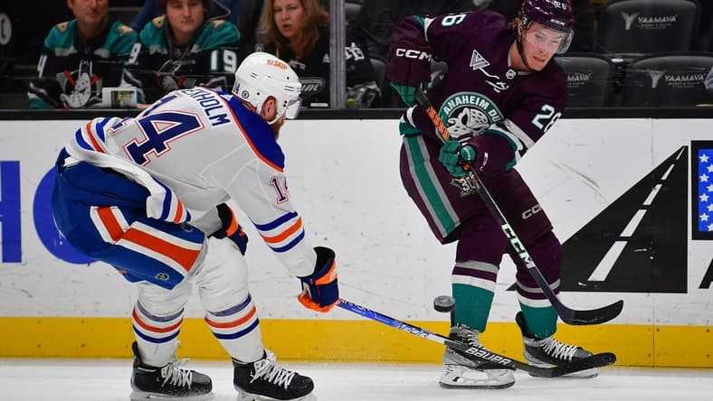 Dec 31, 2023; Anaheim, California, USA; Anaheim Ducks left wing Brock McGinn (26) passes the puck against Edmonton Oilers defenseman Mattias Ekholm (14) during the second period at Honda Center. Mandatory Credit: Gary A. Vasquez-USA TODAY Sports