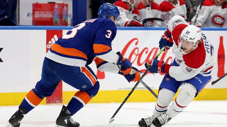 Apr 12, 2023; Elmont, New York, USA; Montreal Canadiens center Rem Pitlick (32) and New York Islanders defenseman Adam Pelech (3) fight for the puck during the first period at UBS Arena. Mandatory Credit: Brad Penner-USA TODAY Sports