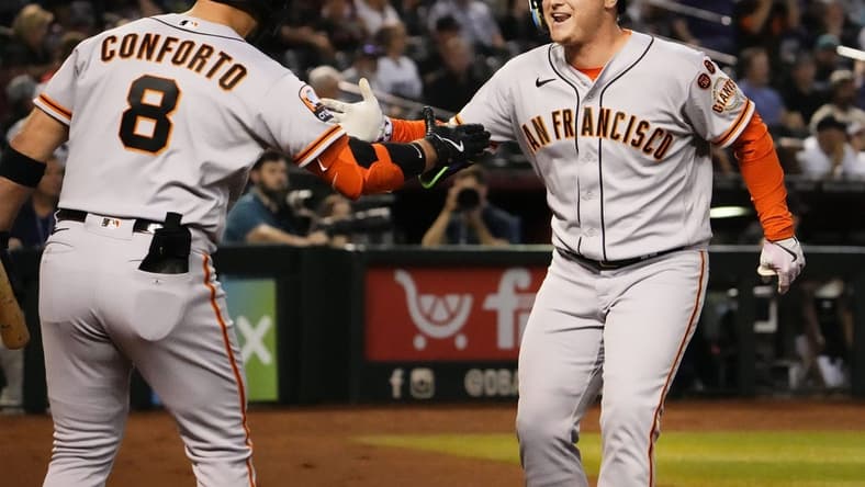 San Francisco Giants designated hitter Joc Pederson (right) reacts after hitting a home run off of Arizona Diamondbacks starting pitcher Zac Gallen (23) in the first inning at Chase Field in Phoenix on Sept. 19, 2023.
