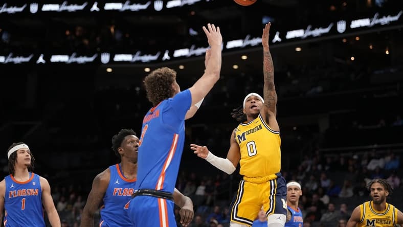 Dec 19, 2023; Charlotte, North Carolina, USA; Michigan Wolverines guard Dug McDaniel (0) goes up for a shot defended by Florida Gators center Micah Handlogten (3) during the first half at Spectrum Center. Mandatory Credit: Jim Dedmon-USA TODAY Sports