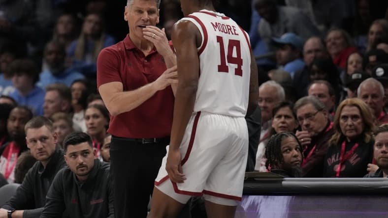 Dec 20, 2023; Charlotte, North Carolina, USA; Oklahoma Sooners head coach Porter Moser talks with forward Jalon Moore (14) during a time out against the North Carolina Tar Heels during the first half at Spectrum Center. Mandatory Credit: Jim Dedmon-USA TODAY Sports
