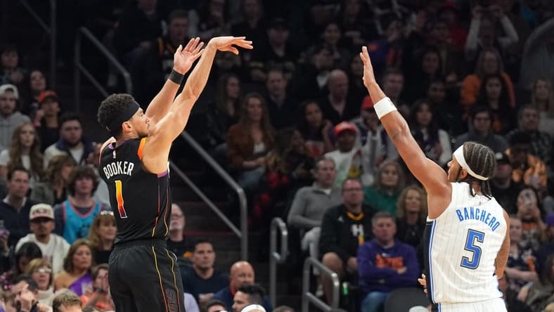 Dec 31, 2023; Phoenix, Arizona, USA; Phoenix Suns guard Devin Booker (1) shoots over Orlando Magic forward Paolo Banchero (5) during the second half at Footprint Center. Mandatory Credit: Joe Camporeale-USA TODAY Sports