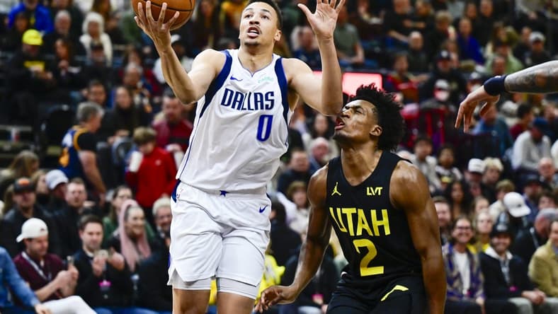 Jan 1, 2024; Salt Lake City, Utah, USA; Dallas Mavericks guard Dante Exum (0) takes a shot in front of Utah Jazz guard Collin Sexton (2) during the first half at the Delta Center. Mandatory Credit: Christopher Creveling-USA TODAY Sports