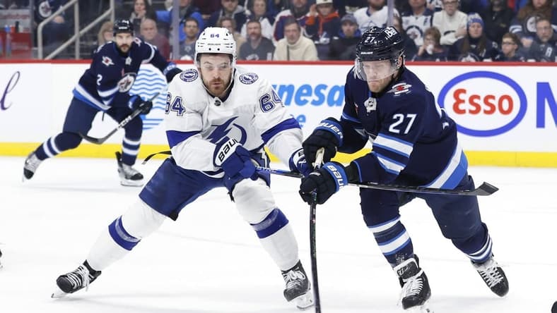 Jan 2, 2024; Winnipeg, Manitoba, CAN; Winnipeg Jets left wing Nikolaj Ehlers (27) is stick checked by Tampa Bay Lightning center Tyler Motte (64) in the first period at Canada Life Centre. Mandatory Credit: James Carey Lauder-USA TODAY Sports