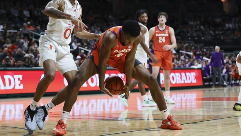 Jan 3, 2024; Coral Gables, Florida, USA; Clemson Tigers forward RJ Godfrey (10) protects the basketball from Miami Hurricanes guard Matthew Cleveland (0) during the first half at Watsco Center. Mandatory Credit: Sam Navarro-USA TODAY Sports