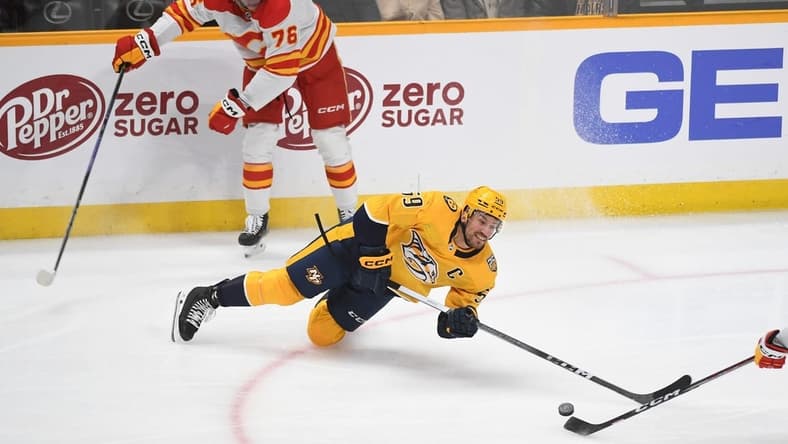 Jan 4, 2024; Nashville, Tennessee, USA; Nashville Predators defenseman Roman Josi (59) loses the puck as he falls to the ice after a hit by Calgary Flames center Martin Pospisil (76) during the first period at Bridgestone Arena. Mandatory Credit: Christopher Hanewinckel-USA TODAY Sports