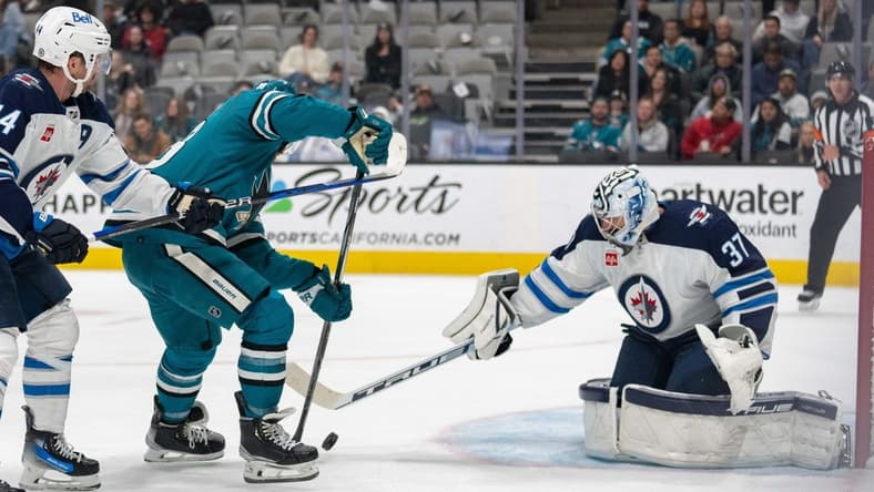 Jan 4, 2024; San Jose, California, USA; Winnipeg Jets goaltender Connor Hellebuyck (37) defends against San Jose Sharks defenseman Mario Ferraro (38) during the second period at SAP Center at San Jose. Mandatory Credit: Stan Szeto-USA TODAY Sports