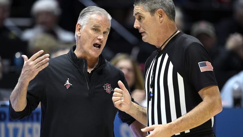 Jan 6, 2024; San Diego, California, USA; San Diego State Aztecs head coach Brian Dutcher (left) speaks with referee Michael Reed during the second half against the UNLV Rebels at Viejas Arena. Mandatory Credit: Orlando Ramirez-USA TODAY Sports