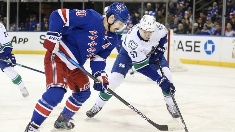 Jan 8, 2024; New York, New York, USA; New York Rangers left wing Chris Kreider (20) and Vancouver Canucks defenseman Tyler Myers (57) battle for control of the puck in the first period at Madison Square Garden. Mandatory Credit: Wendell Cruz-USA TODAY Sports