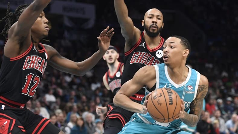 Jan 8, 2024; Charlotte, North Carolina, USA; Charlotte Hornets guard Nick Smith Jr. (8) looks to shoot as he is defended by Chicago Bulls guard Aye Dosunmu (12) and guard Jevon Carter (5) during the first half at the Spectrum Center. Mandatory Credit: Sam Sharpe-USA TODAY Sports