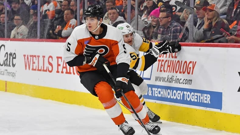 Jan 8, 2024; Philadelphia, Pennsylvania, USA; Philadelphia Flyers defenseman Egor Zamula (5) carries the puck past Pittsburgh Penguins center Noel Acciari (55) during the second period at Wells Fargo Center. Mandatory Credit: Eric Hartline-USA TODAY Sports